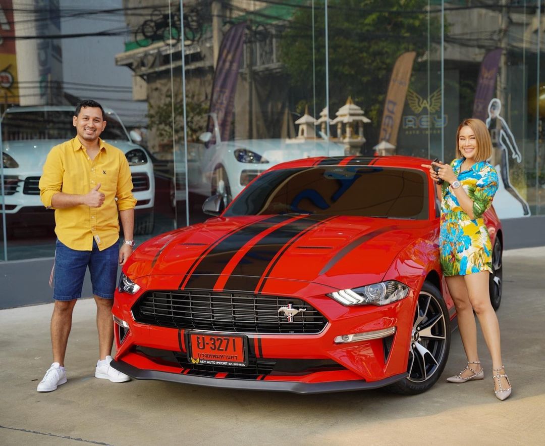 หนูเล็ก ก่อนบ่าย และ เอก เอกวุธ สามี ยืนถ่ายรูปคู่กับรถใหม่ Ford Mustang 2.3L EcoBoost Coupe สีแดง